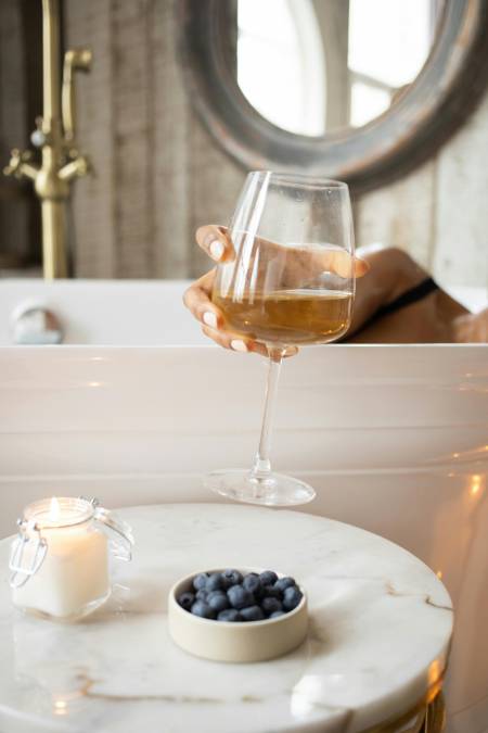 femme dans un bain qui boit un verre de vin blanc